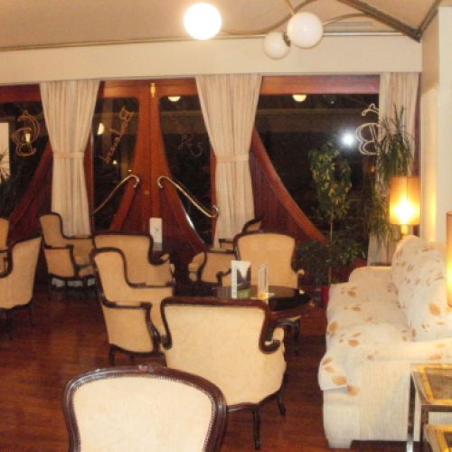 Interior de la cafetería con grupos de sillas clásicas blancas y mesas negras