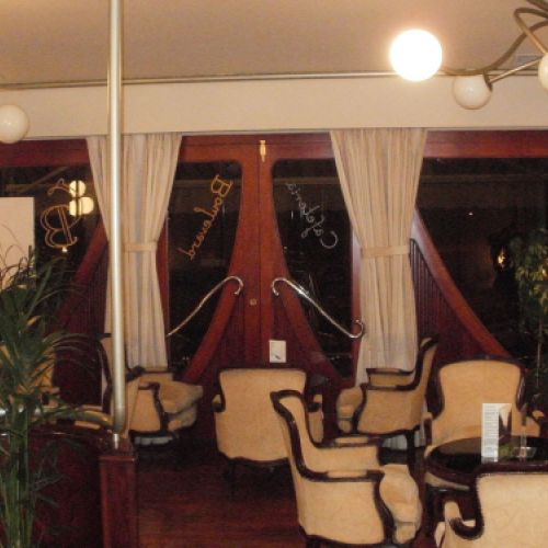 Interior de la cafetería con sillas clásicas blancas y mesas negras