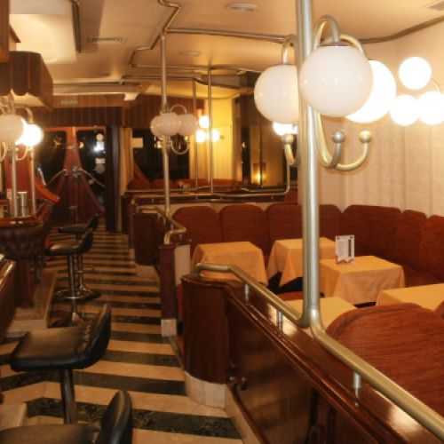 Interior de la cafetería con sillas butacas a la derecha y barra a la izquierda